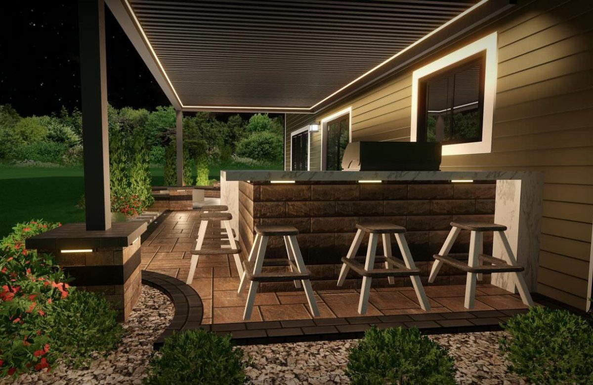 Modern outdoor kitchen with a stone bar, white stools, and a slatted pergola at night.