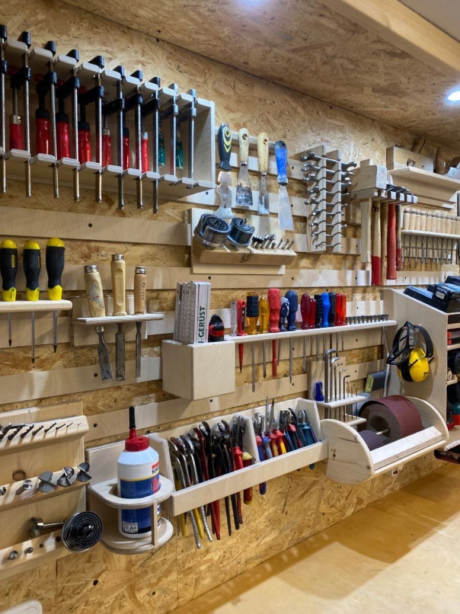 Organized woodworking tools stored in custom wooden racks on a workshop wall.