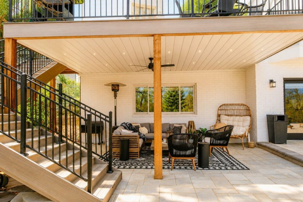 Outdoor living room furniture set on a stone patio under a wooden deck ceiling.